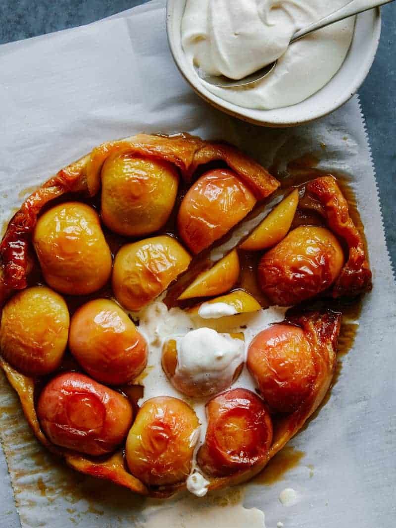 A close up of sliced honey crisp apple tart tatin with melting whipped cream.