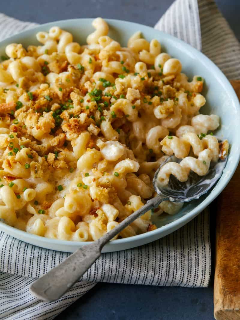 Taleggio mac and cheese topped with buttery crackers with a spoon.