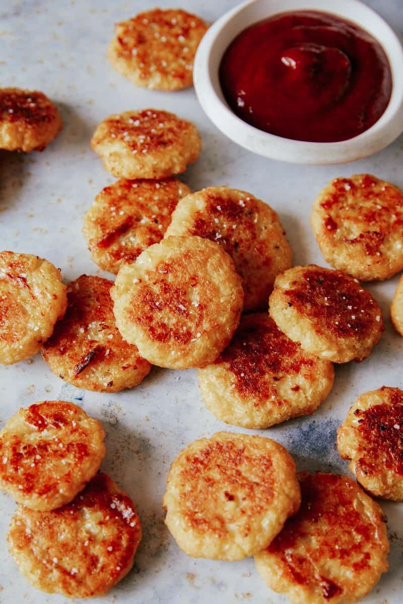 A close up of crispy baked cauliflower tots with sauce.