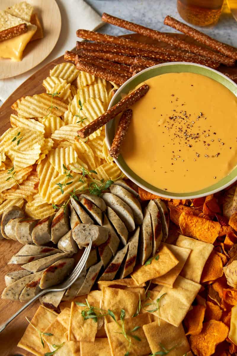 Crock pot beer cheese dip with chips and meat for dipping.