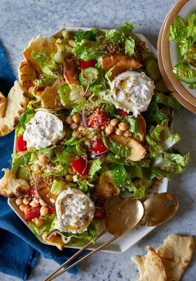 A close up of fattoush style salad with crispy quinoa on a platter.