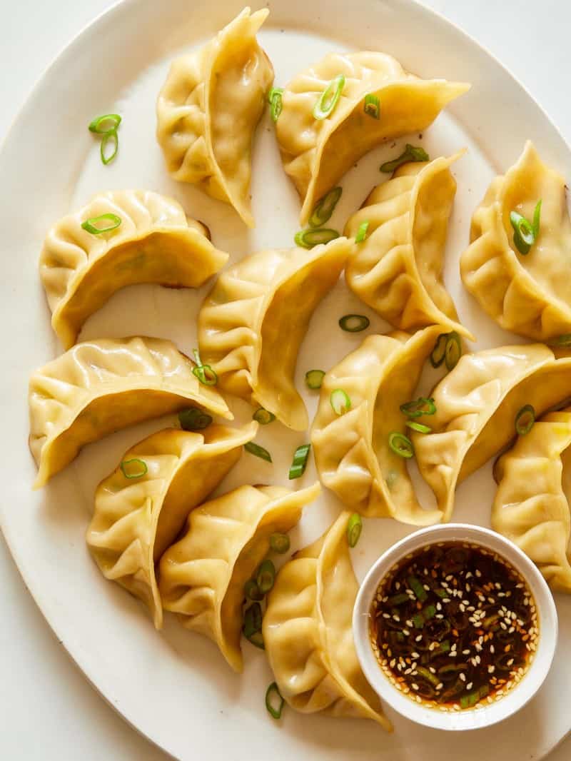 Ginger chicken pot stickers with green onions and sauce on the side.