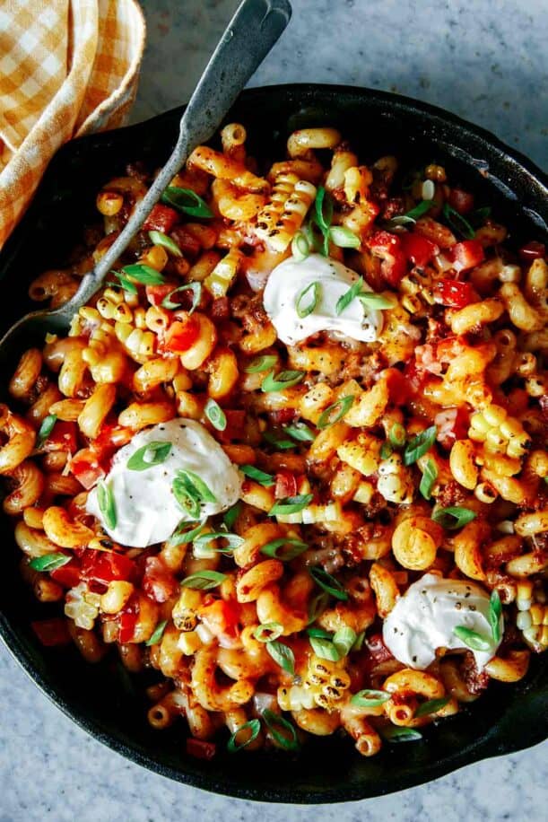 A close up of taco pasta in a skillet with a spoon.