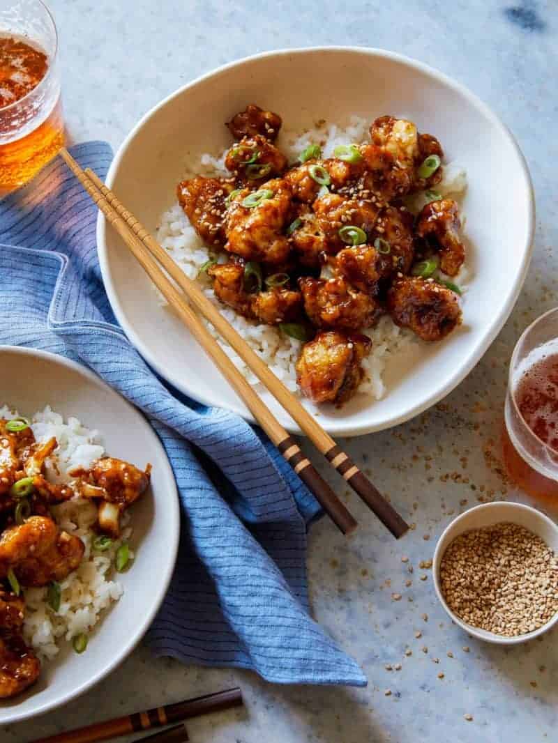 Bowls of honey garlic cauliflower over white rice with chopsticks.