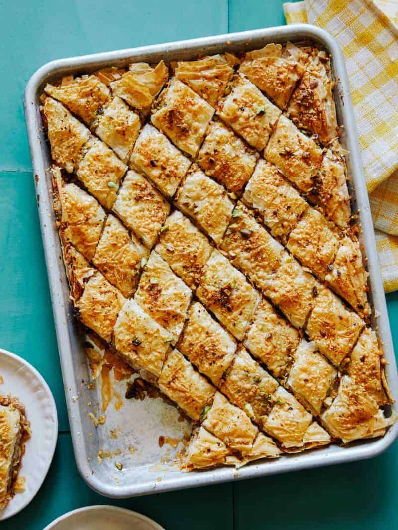 A tray of savory baklava with pieces served on a plate.