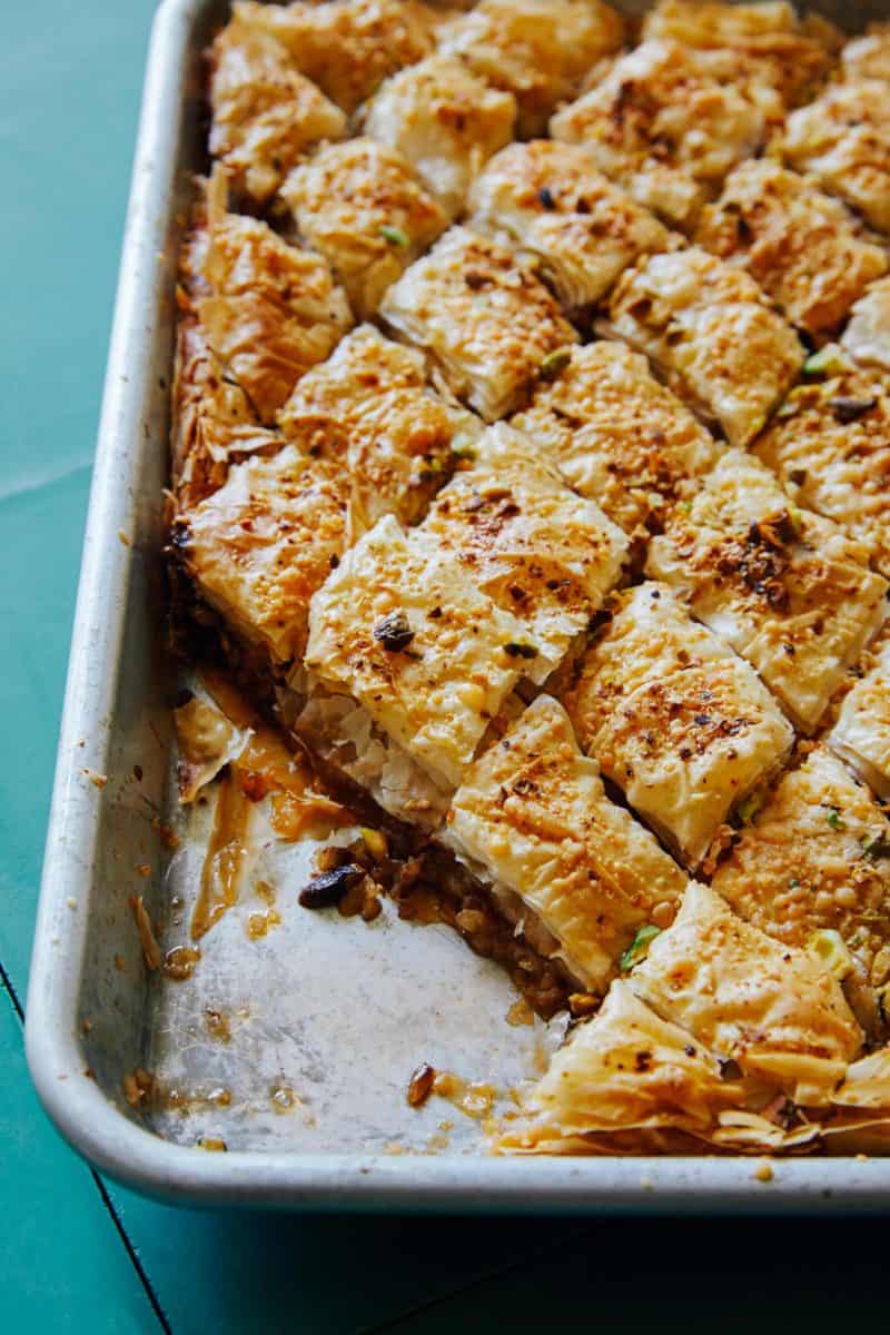 A close up of a tray of savory baklava with pieces taken out.