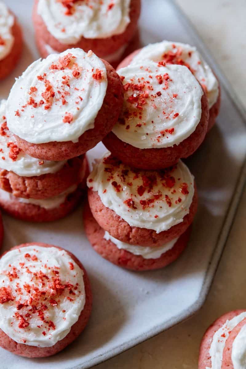 A close up of soft and fluffy strawberry cookies with vanilla frosting.