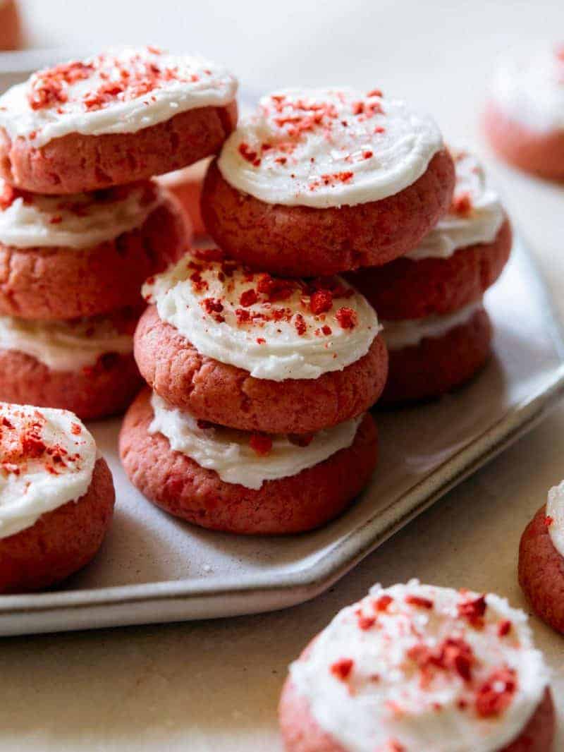 A close up of soft and fluffy strawberry cookies with vanilla frosting.