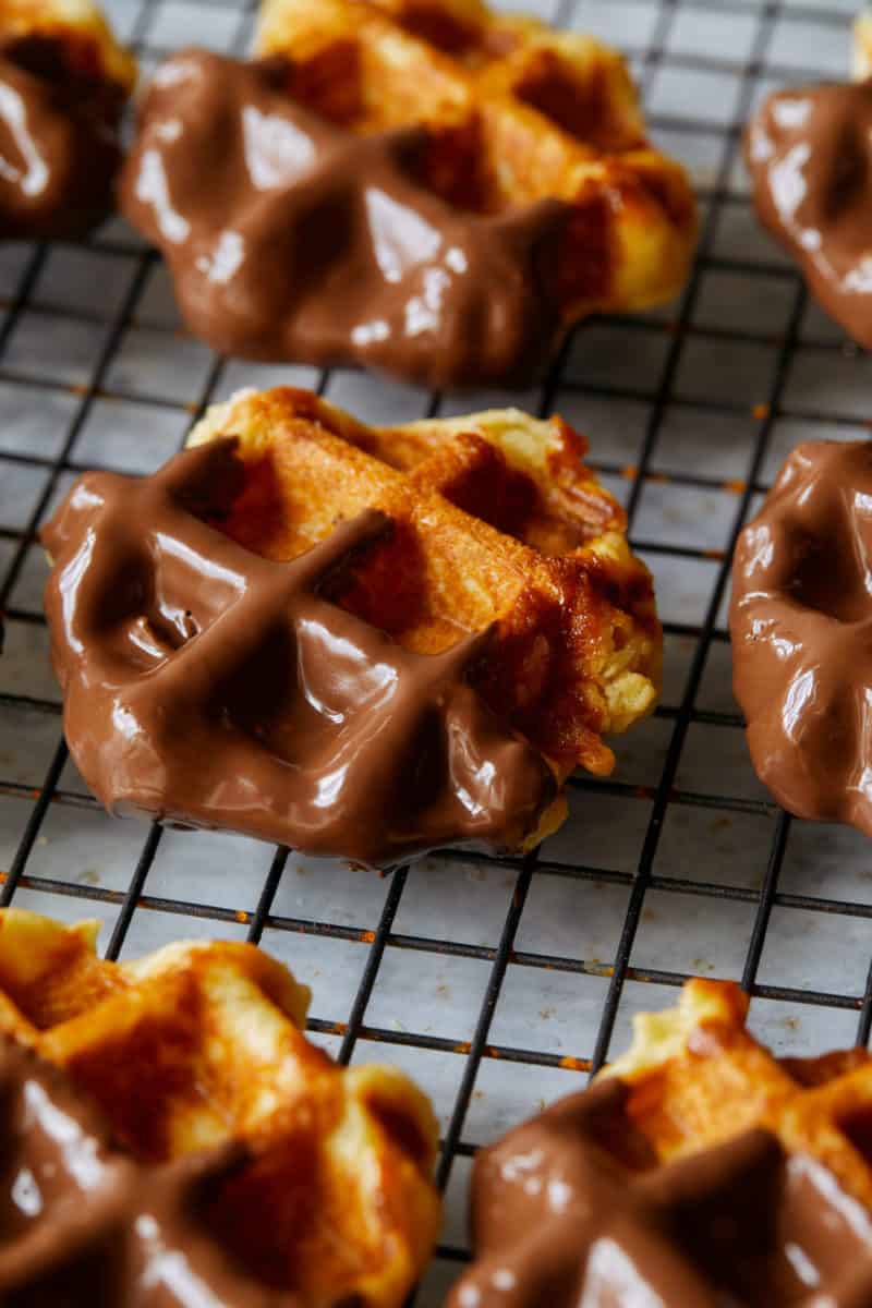 Chocolate dipped liege waffles on a cooling rack.