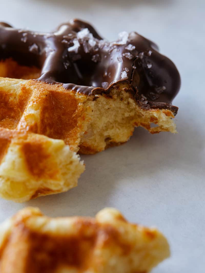 A close up of a salted chocolate dipped liege waffle with a bite out.