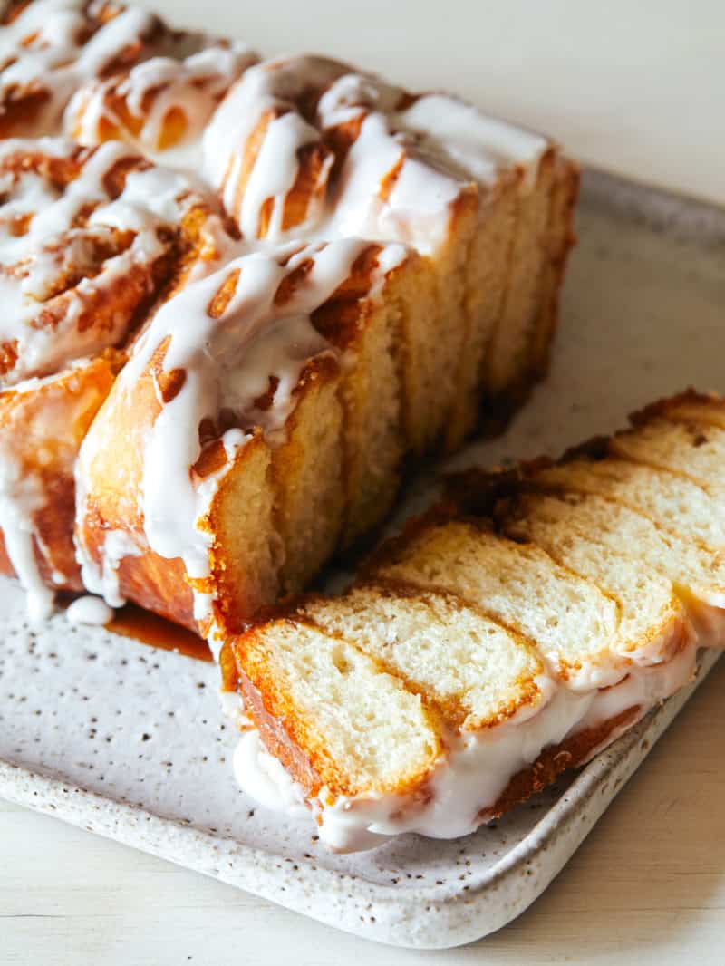 A  frosted cinnamon roll loaf with the end sliced off.