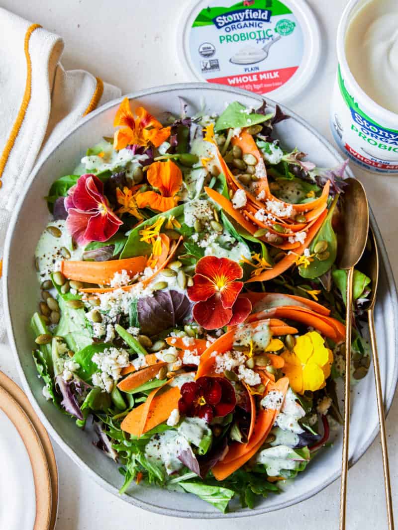 A bowl of summer salad next to Stonyfield organic whole milk yogurt.