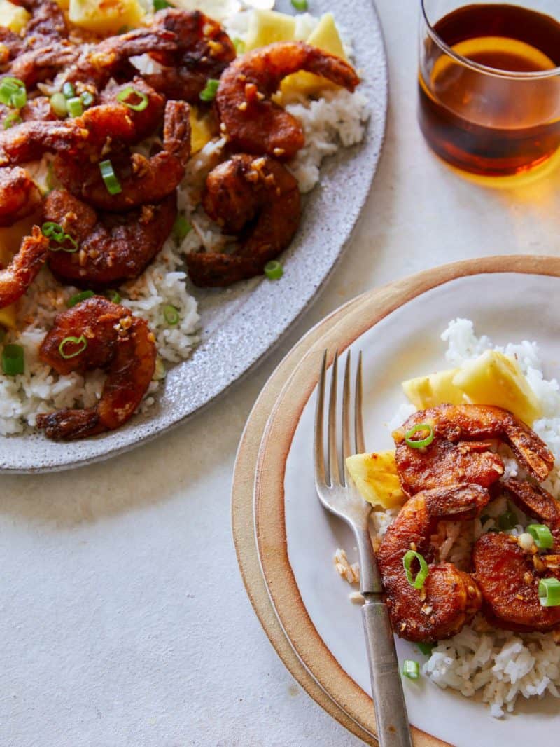 Hawaiian style crispy garlic butter shrimp over white rice, served with a fork.