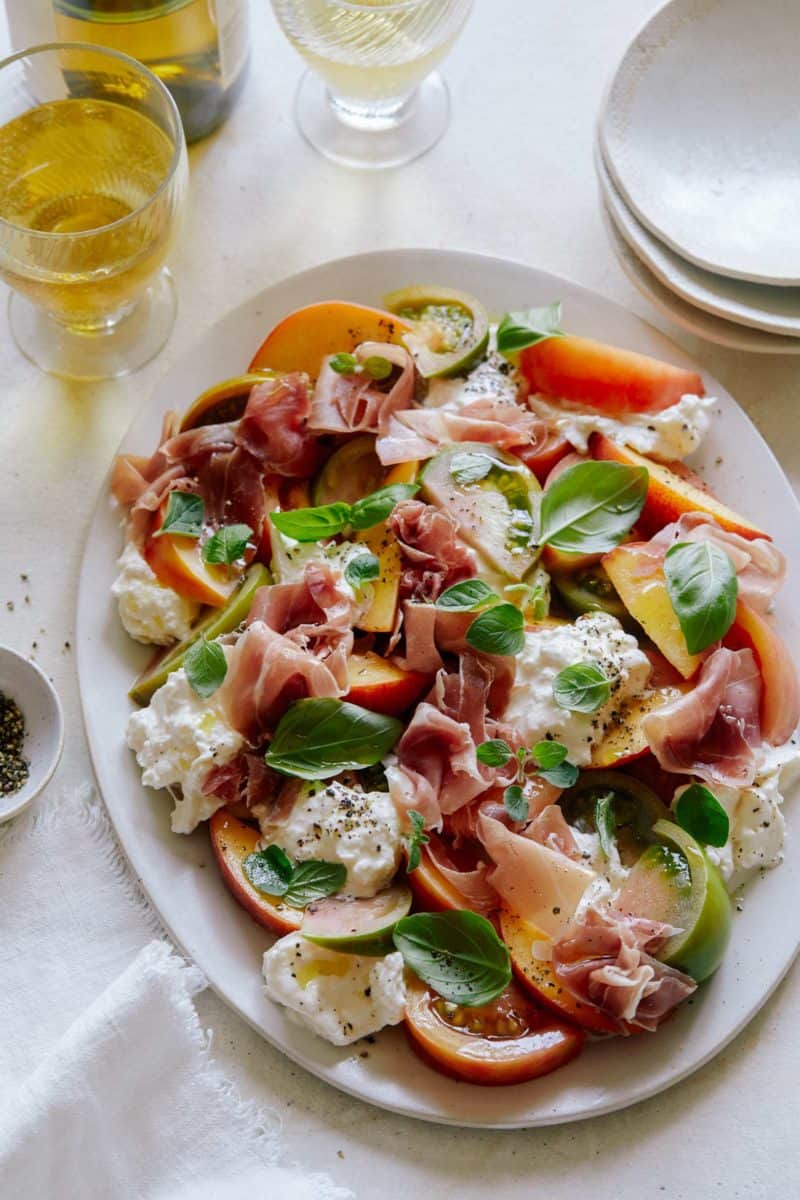 Heirloom tomato, peach, and burrata summer plate with plates.