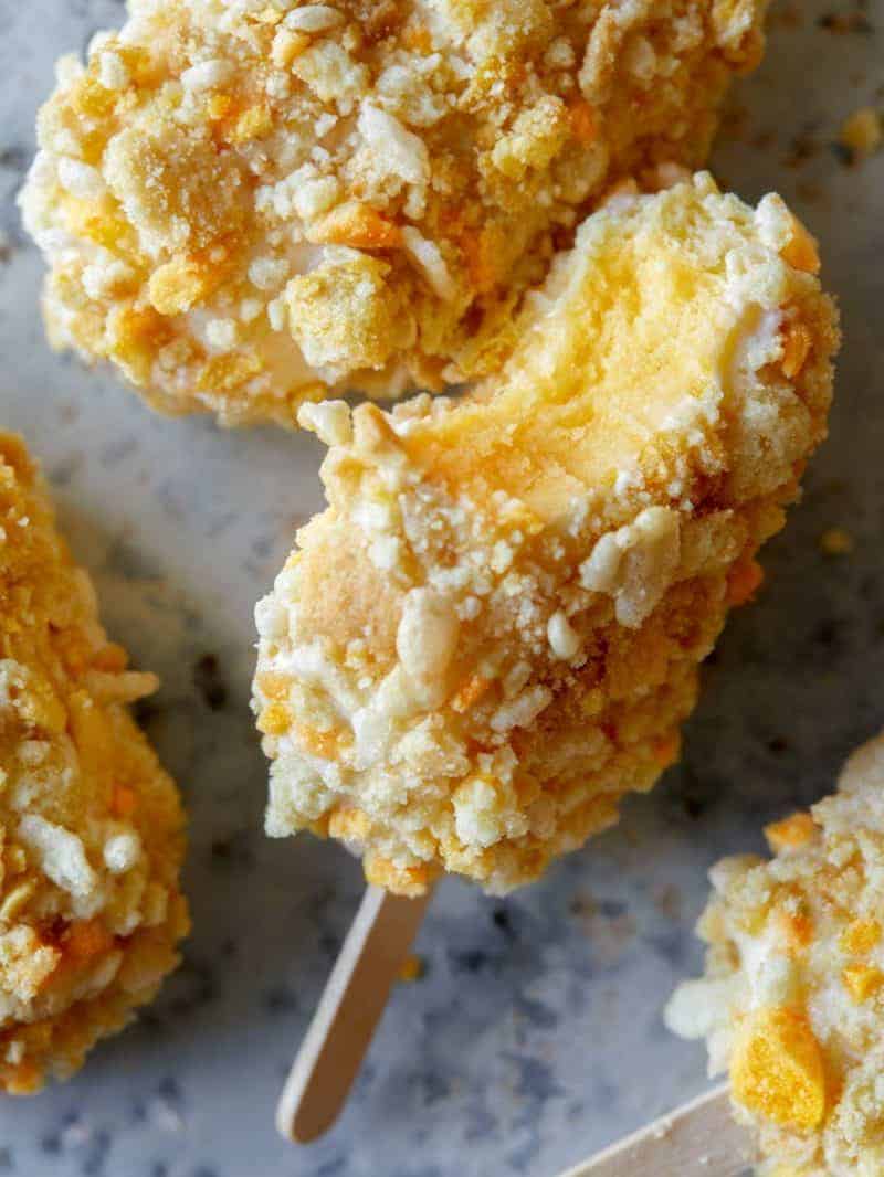 A close up of cookie coated mango Lassi frozen yogurt bar with a bite out.