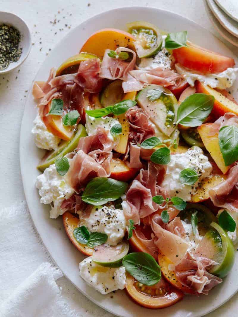 A close up of heirloom tomato, peach, and burrata summer plate.