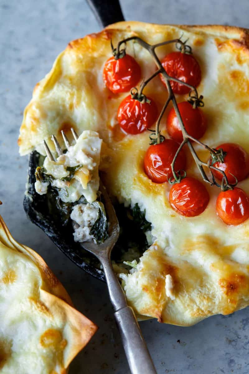 A close up of individual creamy turkey and kale skillet lasagne with a fork.