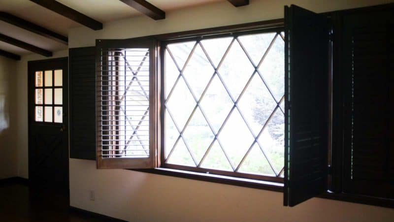 A room with a large window with open shutters.