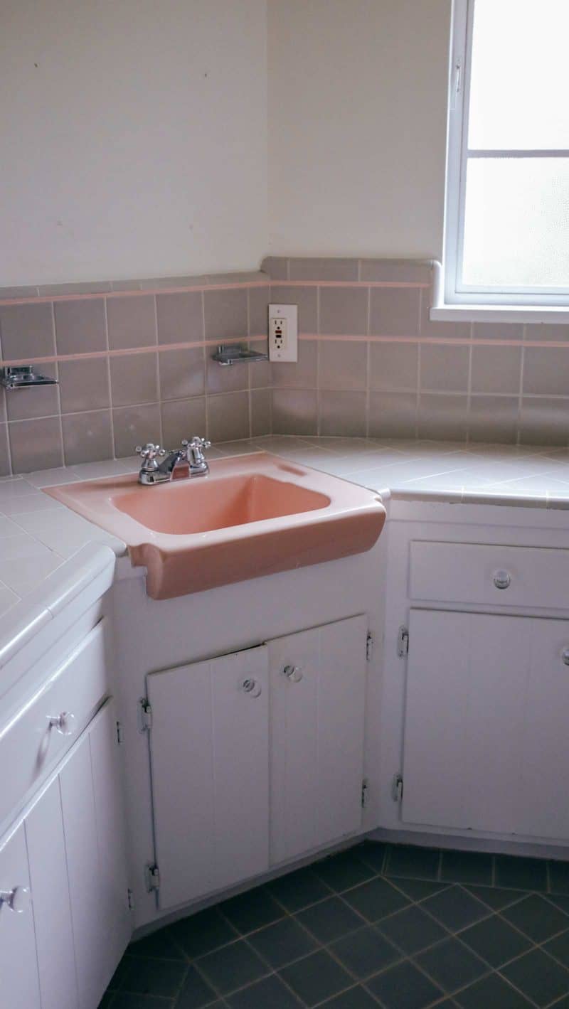 A bathroom counter and pink sink with a window