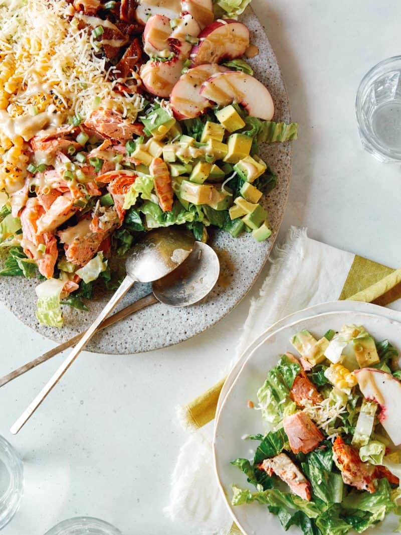 Salmon summer salads served on plates with spoons.