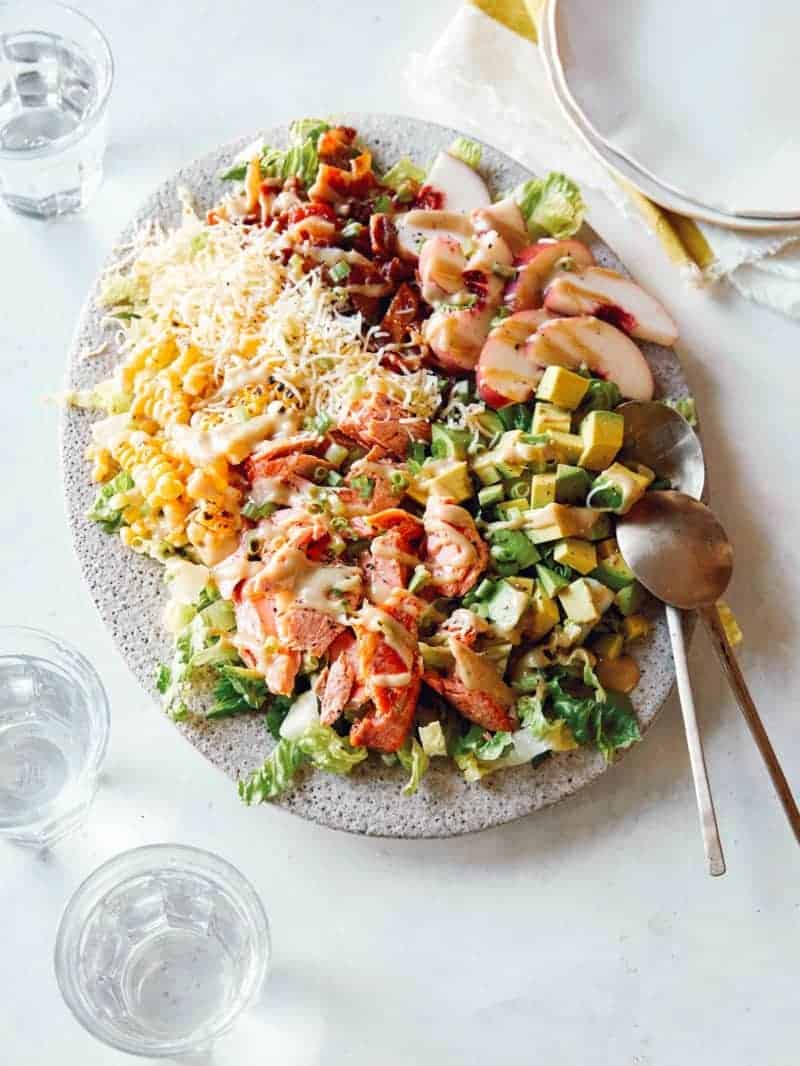 Salmon summer salad on a plate with spoons.