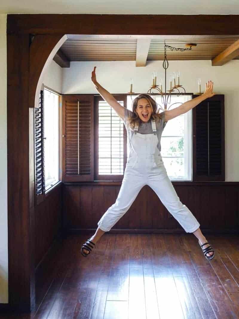 An excited woman jumping in the air with joy in an empty dining room.