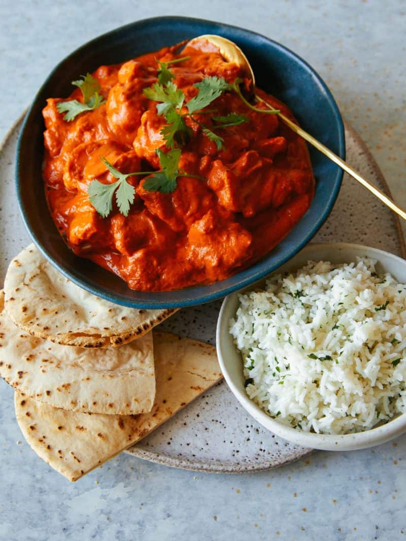 Bowls of Indian butter cauliflower, white rice, and pita bread.