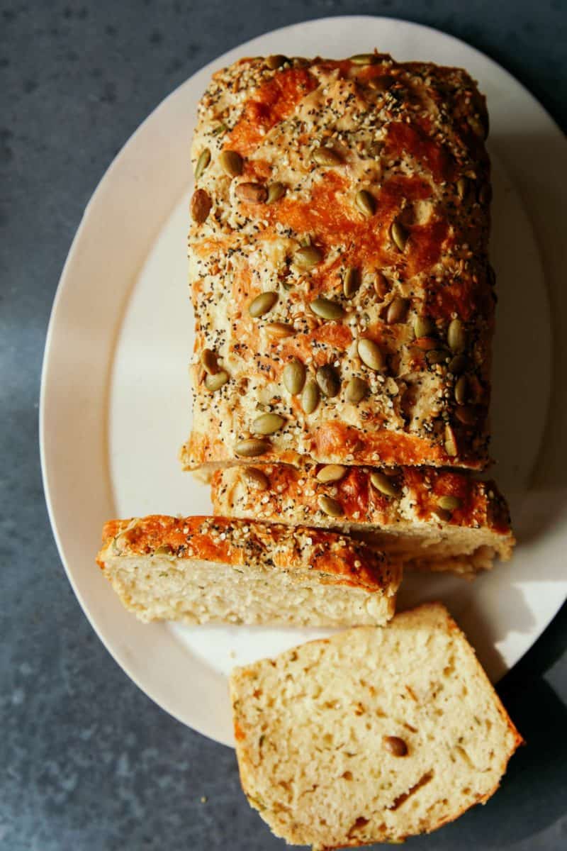 A loaf with some slices of cheesy herb beer bread on  a white plate.