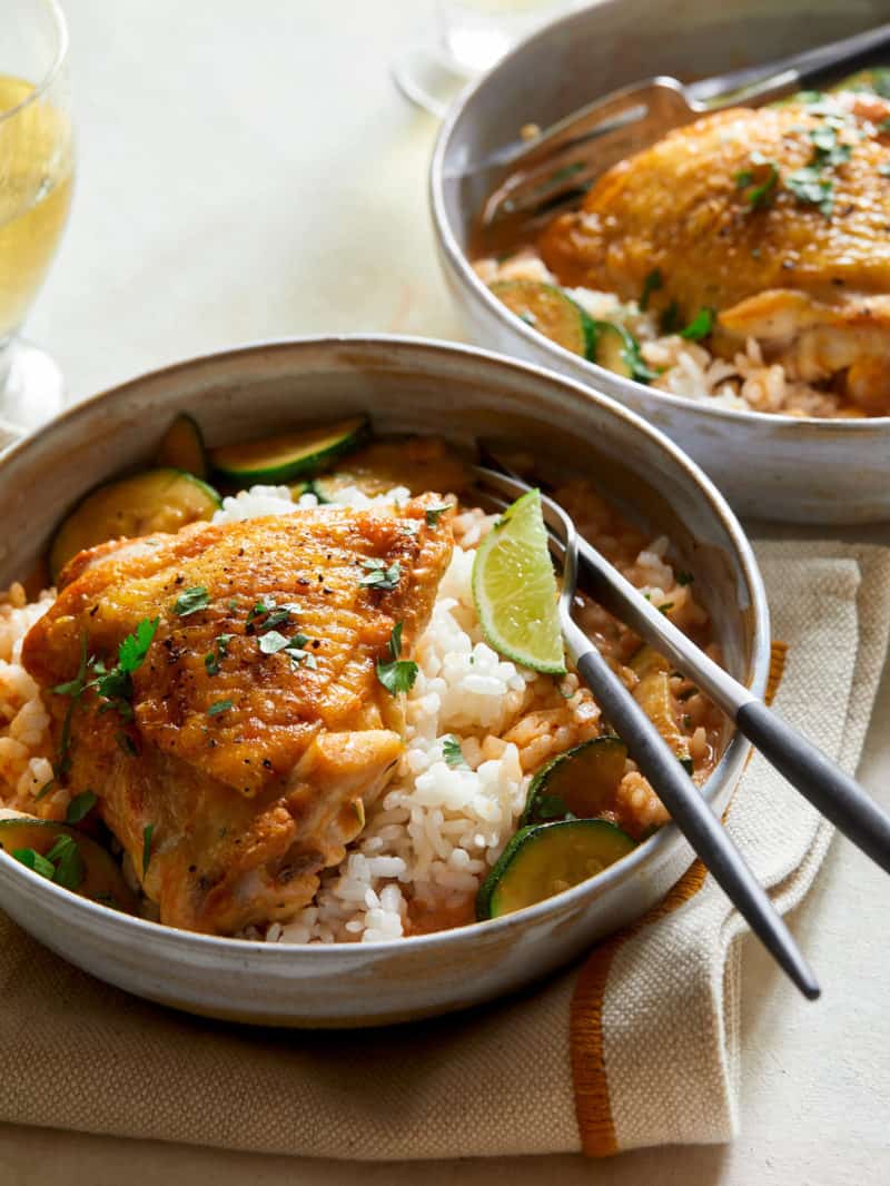 A close up of Thai red curry chicken thighs over white rice with a fork.