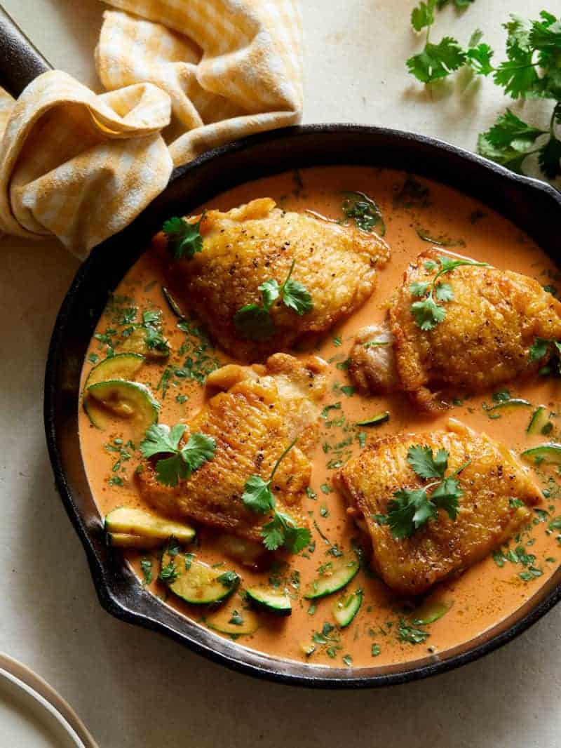 Thai red curry chicken thighs in a pan.