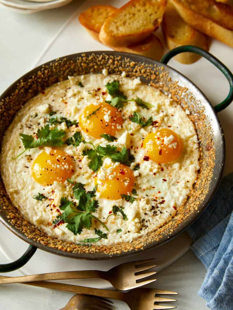 A pan of herb baked eggs with crumbled cheese.