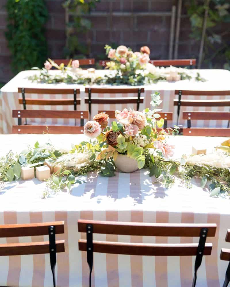 Party tables set with floral arrangement and decorative blocks.