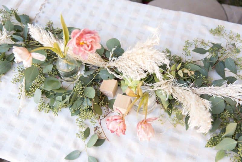 Floral arrangements with decorative blocks and greenery on a table.