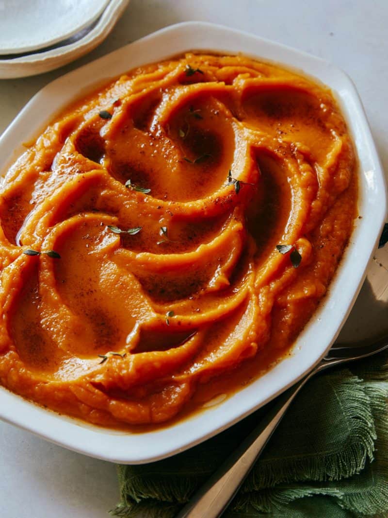 A close up of butternut squash puree in a bowl with a spoon.