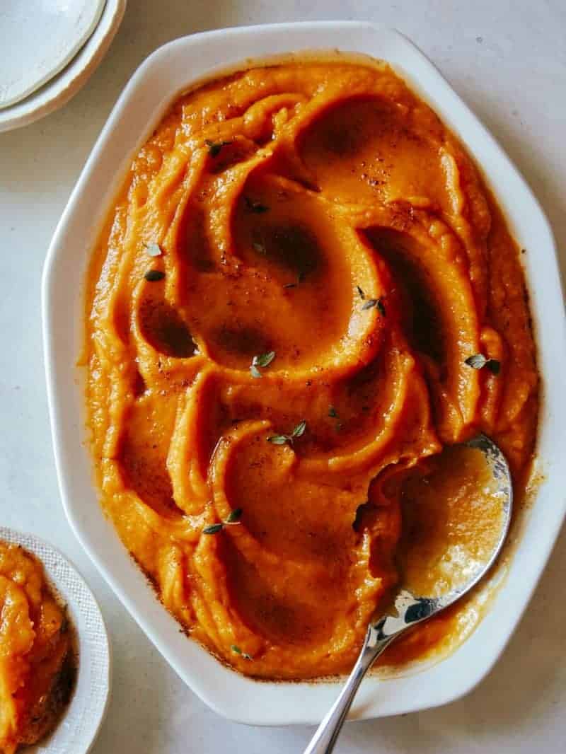 A close up of butternut squash puree in a bowl with a spoon.