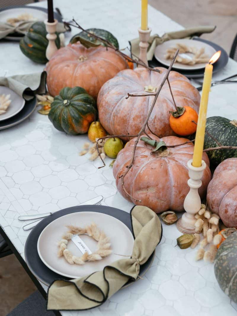 Place settings, winter squash, fruits, dried bunny tails, and candles in center.