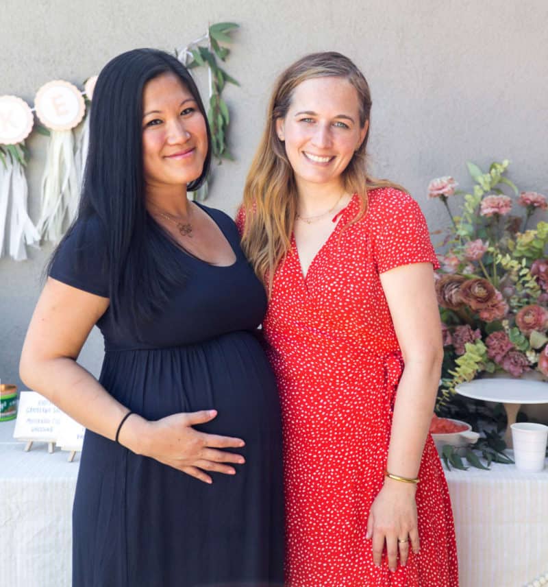 A stunning pregnant woman posing with her gorgeous friend for a photo.