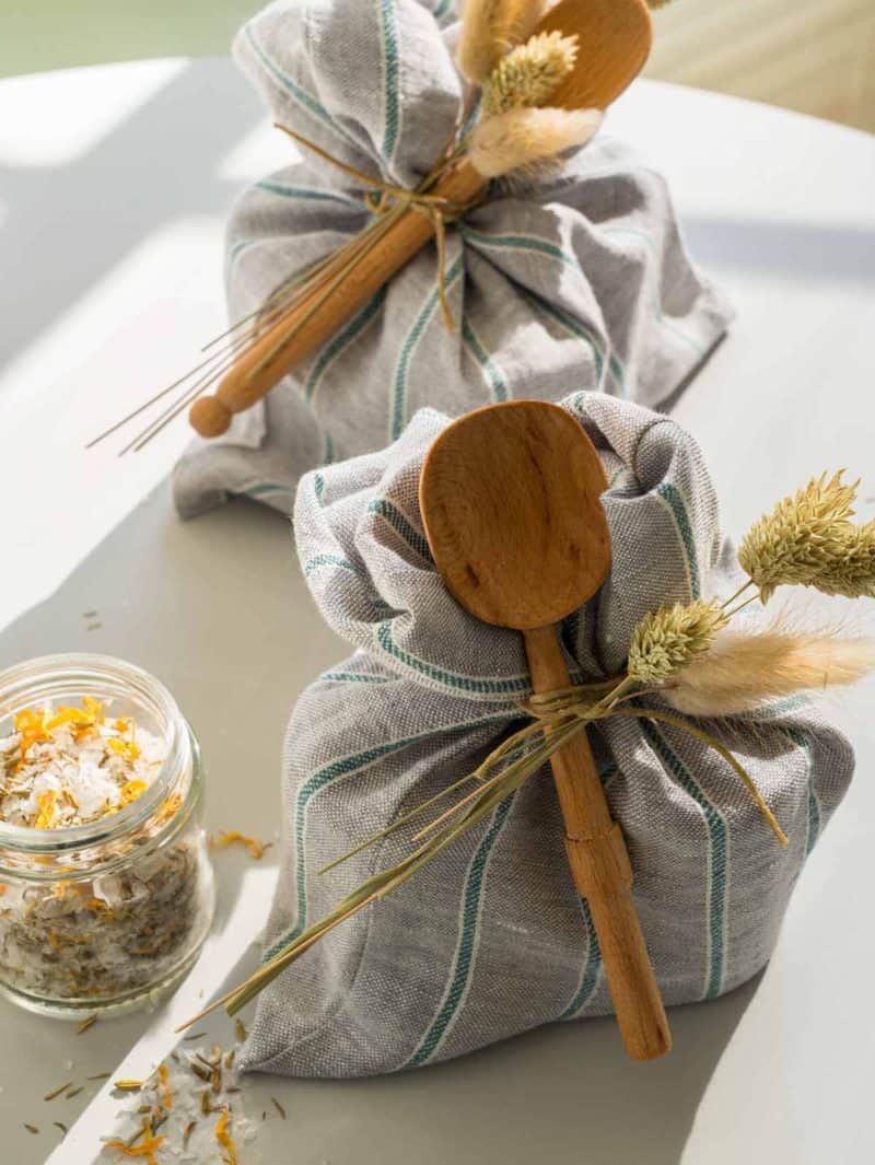 Reusable produce bags tied with dried grass and a wooden spoon.