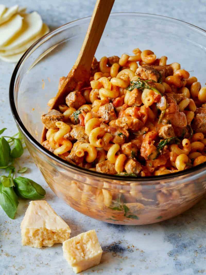 A bowl of creamy baked tomato pasta with a wooden spoon.