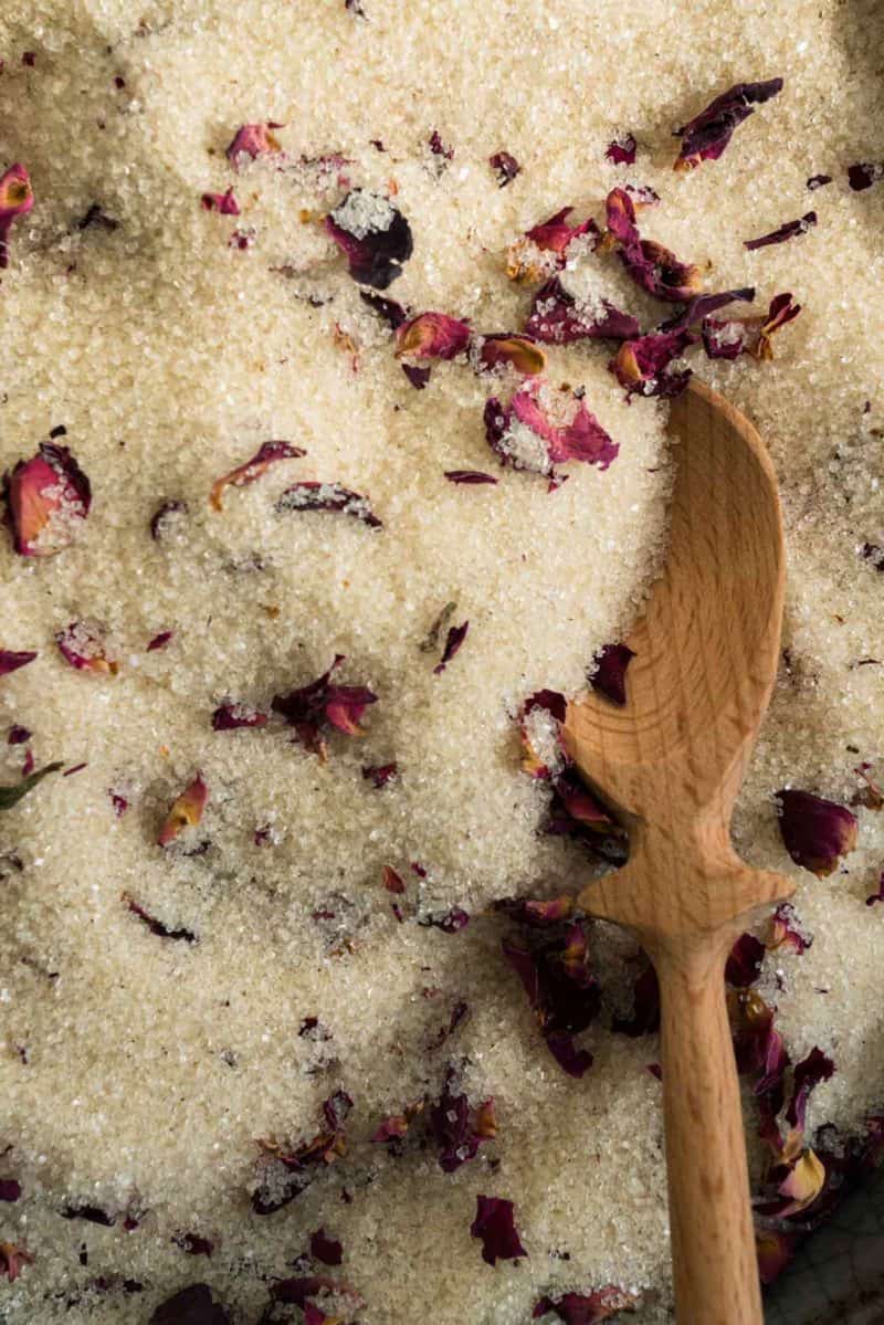 A close up of vanilla rose sugar with a wooden spoon.