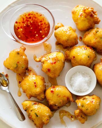 Hush puppies with sauce, salt, and spoon.