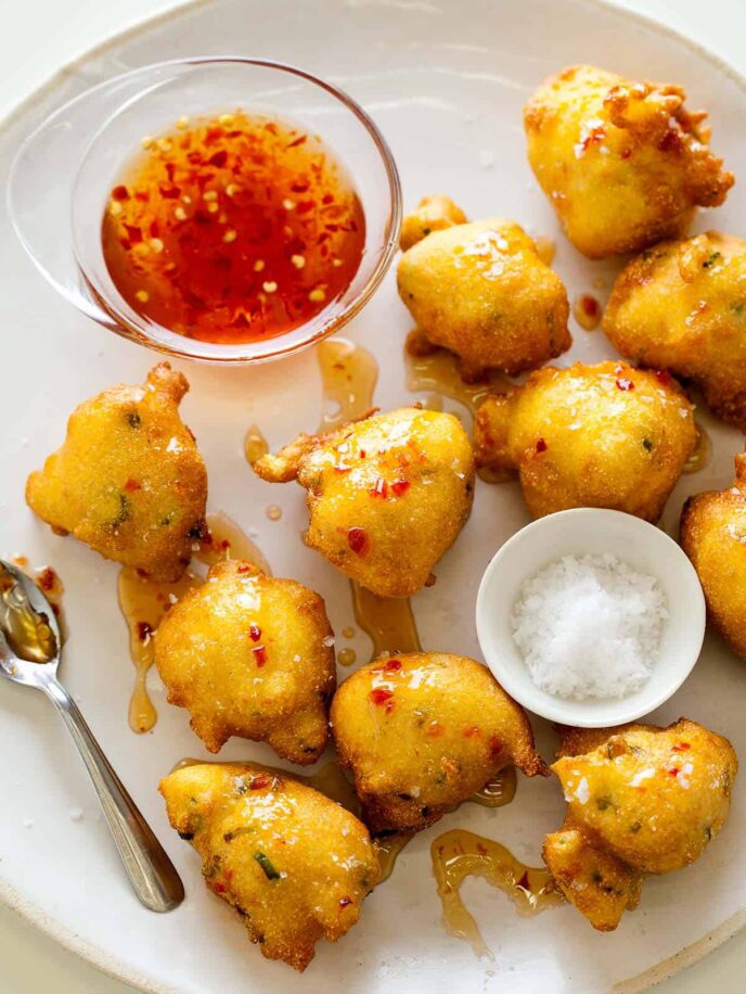 Hush puppies with sauce, salt, and spoon.
