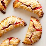 A close up of several cherry hand pies with cherry icing drizzle.