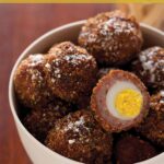 A recipe for mini scotch eggs in a bowl with one cut open.