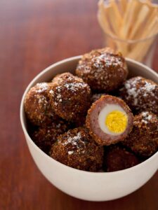 Hard boiled quail egg wrapped in sausage, coated in bread crumbs, then fried.