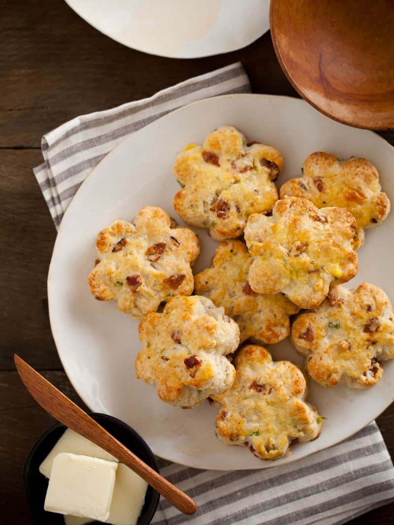 A close up of a plate of bacon gruyere and green onion scones and butter.