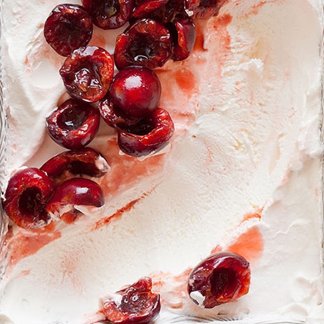 A close up of cherry semifreddo with orange cherry compote with a scoop taken out.