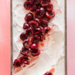 A close up of cherry semifreddo with orange cherry compote with a scoop taken out.