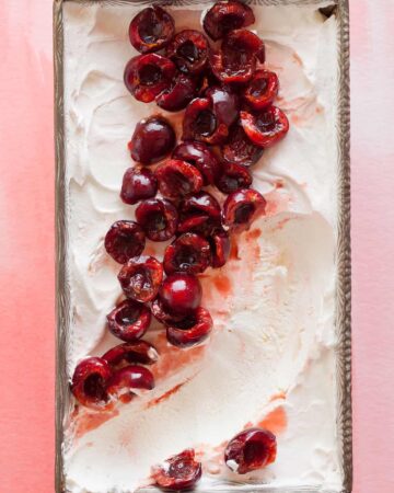 A close up of cherry semifreddo with orange cherry compote with a scoop taken out.