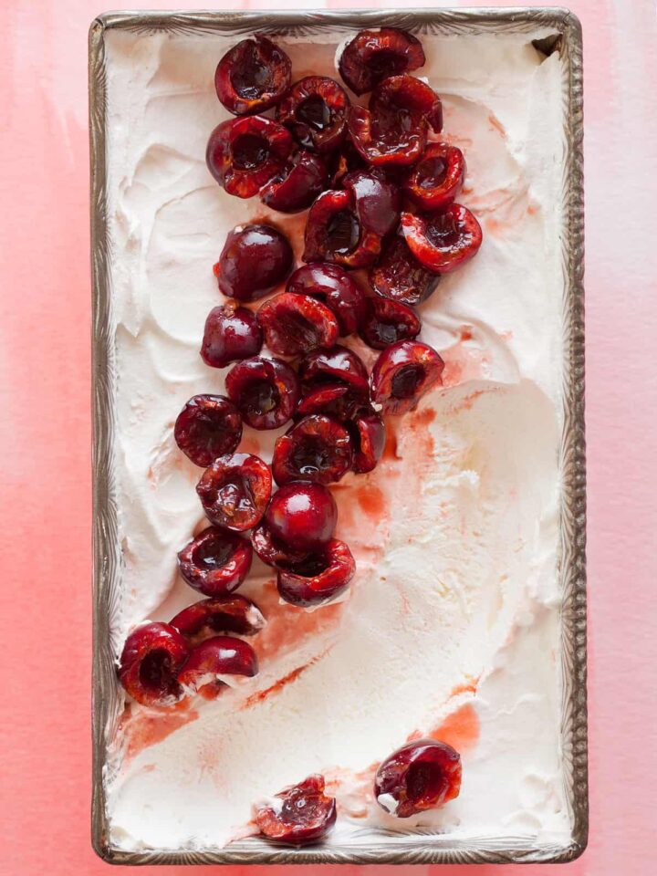 A close up of cherry semifreddo with orange cherry compote with a scoop taken out.